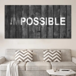 Tableau motivation impossible accroché au-dessus d'un canapé beige avec coussins à motifs